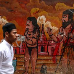 Un devoto musulmán pasa junto a un mural al salir tras realizar las oraciones del Eid al-Fitr, que marca el final del mes sagrado de ayuno islámico del Ramadán, en la mezquita de Alamgir, a orillas del río Ganges en Varanasi, India. | Foto:NIHARIKA KULKARNI / AFP