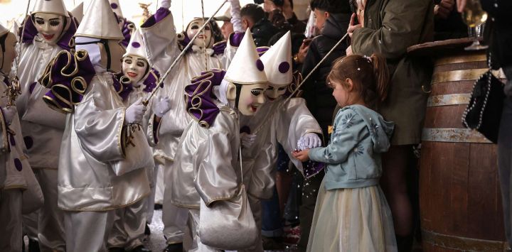 Artistas enmascarados lanzan confeti a una niña durante el último día del carnaval de la ciudad en el centro histórico de Limoux, en el sur de Francia.