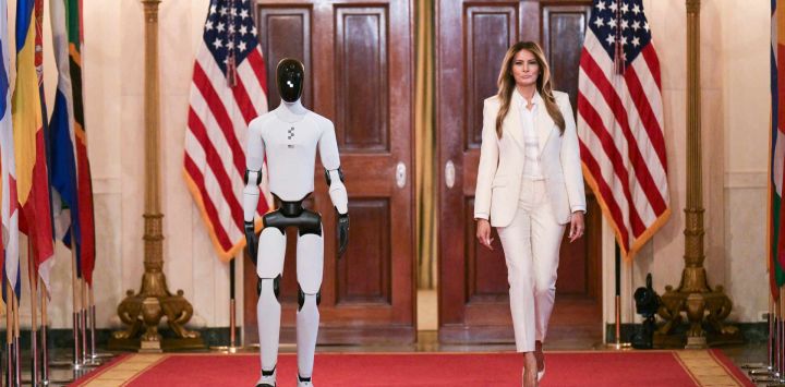 La primera dama estadounidense, Melania Trump, camina acompañada de un robot humanoide a su llegada a la Cumbre de la Coalición Global "Fomentando el Futuro Juntos" en el Salón Este de la Casa Blanca en Washington, D.C..
