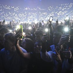 Los fans sostienen sus teléfonos inteligentes con el flash activado durante un concierto en homenaje al fallecido rapero francés Werenoi en el Accor Arena de París. | Foto:JULIEN DE ROSA / AFP
