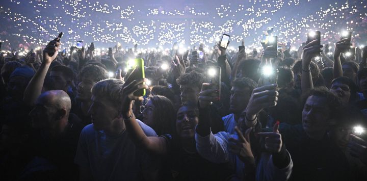 Los fans sostienen sus teléfonos inteligentes con el flash activado durante un concierto en homenaje al fallecido rapero francés Werenoi en el Accor Arena de París.