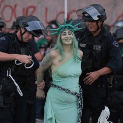 Agentes del Departamento de Policía de Los Ángeles (LAPD) arrestaron a una manifestante vestida como la Estatua de la Libertad encadenada tras enfrentamientos cerca del Centro de Detención Metropolitano durante la jornada nacional de protesta "No Kings" en Los Ángeles. Multitudes de manifestantes se congregaron en todo Estados Unidos contra el presidente Donald Trump, expresando su furia por lo que consideran su estilo de gobierno autoritario, sus políticas migratorias de línea dura y la guerra con Irán. Los organizadores afirmaron que "al menos 8 millones de personas se reunieron en más de 3300 eventos en los 50 estados", tanto en grandes ciudades como en pequeños pueblos. Las autoridades estadounidenses no proporcionaron una estimación nacional de la multitud. | Foto:ETIENNE LAURENT / AFP