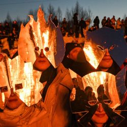 Espectadores disfrazados observan la quema del "Corazón Ardiente", una estructura de madera creada por el artista ruso Nikolay Polissky, durante las celebraciones de "Maslenitsa", la festividad eslava oriental del Carnaval, en la aldea de Nikola-Lenivets, región de Kaluga, a unos 220 km (140 millas) de Moscú. El Carnaval o Maslenitsa es una antigua ceremonia de despedida del invierno, que se celebra tradicionalmente en Bielorrusia, Rusia y Ucrania e incluye la quema de una gran efigie. | Foto:Hector Retamal / AFP