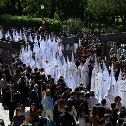Penitentes de la hermandad de La Paz participan en la procesión del Domingo de Ramos en Sevilla. Las coloridas celebraciones de la Semana Santa en España comienzan con procesiones centenarias de fieles que portan carrozas adornadas con flores y coronadas con estatuas de Cristo o la Virgen María, que congregan a multitudes. | Foto:CRISTINA QUICLER / AFP