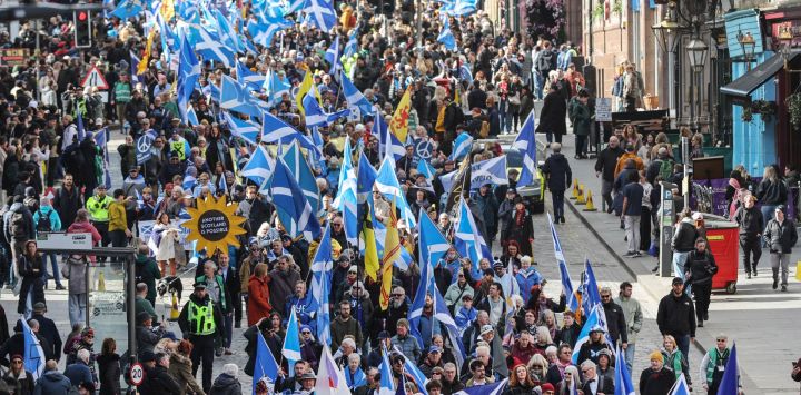En Edimburgo, la gente ondea banderas escocesas y porta pancartas mientras marcha en apoyo a la independencia de Escocia.