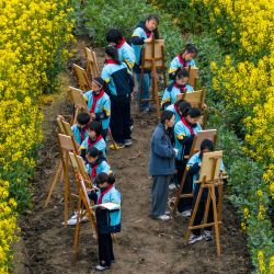 Estudiantes participan en una actividad de dibujo al aire libre en un campo de colza durante las vacaciones de primavera en el distrito de Jiangyan, Taizhou, en la provincia oriental china de Jiangsu. | Foto:CN-STR / AFP