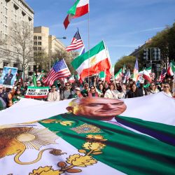 Manifestantes ondean banderas iraníes (anteriores a la Revolución Islámica de 1979) y estadounidenses, y portan una gran pancarta con la imagen de Reza Pahlavi, hijo del último sha de Irán, mientras marchan hacia la Casa Blanca durante una concentración en apoyo a la lucha por la libertad del pueblo iraní, en Washington, D.C.. El evento, organizado por DCProtests4Iran, reunió a miembros de la diáspora iraní del área metropolitana de Washington, D.C. y estados aledaños. | Foto:AMID FARAHI / AFP