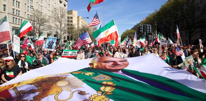 Manifestantes ondean banderas iraníes (anteriores a la Revolución Islámica de 1979) y estadounidenses, y portan una gran pancarta con la imagen de Reza Pahlavi, hijo del último sha de Irán, mientras marchan hacia la Casa Blanca durante una concentración en apoyo a la lucha por la libertad del pueblo iraní, en Washington, D.C.. El evento, organizado por DCProtests4Iran, reunió a miembros de la diáspora iraní del área metropolitana de Washington, D.C. y estados aledaños.