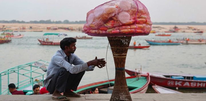 Un vendedor ambulante de aperitivos espera a los clientes a orillas del río Ganges en Meer Ghat, Varanasi, India.