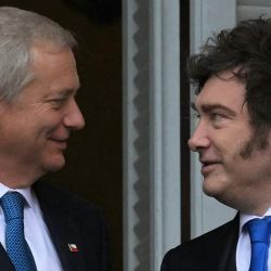 El presidente de Chile, José Antonio Kast y el presidente de Argentina, Javier Milei, se miran en el balcón de la Casa Rosada, palacio de gobierno, tras una reunión en Buenos Aires. El primer viaje al extranjero de Kast desde que asumió el cargo en marzo continúa la tradición de que los presidentes chilenos realicen su primer viaje oficial de Estado a Argentina. Con una afinidad política similar, Kast y el presidente libertario argentino, Javier Milei, son aliados cercanos del presidente estadounidense Donald Trump y forman parte del creciente giro a la derecha en la región. | Foto:JUAN MABROMATA / AFP