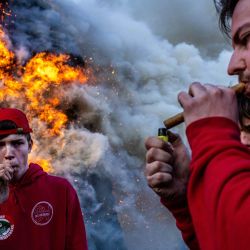 Los constructores de hogueras encienden puros mientras se enciende una hoguera en la aldea de Beuseberg, cerca de Holten, Países Bajos. | Foto:Vincent Jannink / ANP / AFP