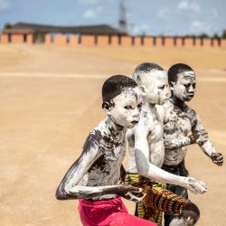 Niños cubiertos de polvo blanco posan para una fotografía cerca del monumento de la Puerta del No Retorno en Ouidah, Benín. | Foto:OLYMPIA DE MAISMONT / AFP