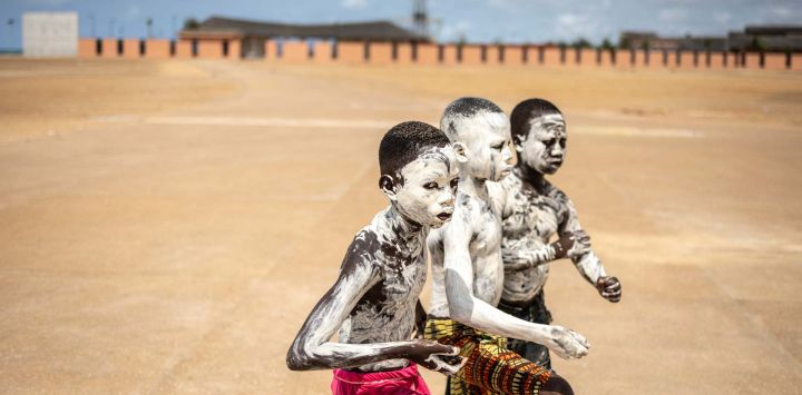 Niños cubiertos de polvo blanco posan para una fotografía cerca del monumento de la Puerta del No Retorno en Ouidah, Benín.