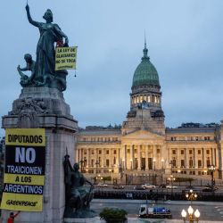 Activistas de Greenpeace exhiben pancartas con los lemas “La Ley de Glaciares permanece intacta” y “Diputados, no traicionen a los argentinos” en un monumento frente al edificio del Congreso en Buenos Aires. Los diputados argentinos debatirán una propuesta del gobierno que solicita a las provincias la redefinición de las zonas de protección glaciar para expandir las operaciones mineras. | Foto:Tomas Cuesta / AFP