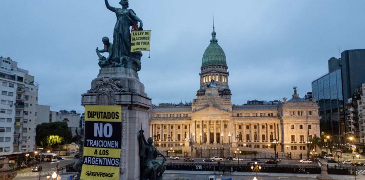 Activistas de Greenpeace exhiben pancartas con los lemas “La Ley de Glaciares permanece intacta” y “Diputados, no traicionen a los argentinos” en un monumento frente al edificio del Congreso en Buenos Aires. Los diputados argentinos debatirán una propuesta del gobierno que solicita a las provincias la redefinición de las zonas de protección glaciar para expandir las operaciones mineras.