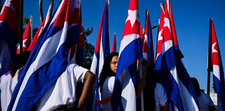 Una mujer observa entre banderas cubanas mientras participa en una manifestación de mujeres contra las sanciones impuestas por Estados Unidos a Cuba, incluido el embargo petrolero vigente desde enero, en La Habana.