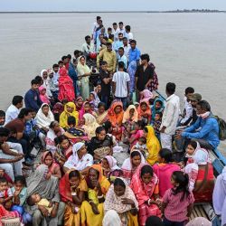 Varias personas viajan en barco a través del río Brahmaputra para emitir su voto en un colegio electoral durante las elecciones a la Asamblea Legislativa de Assam en el distrito de Darrang, India. | Foto:BIJU BORO / AFP