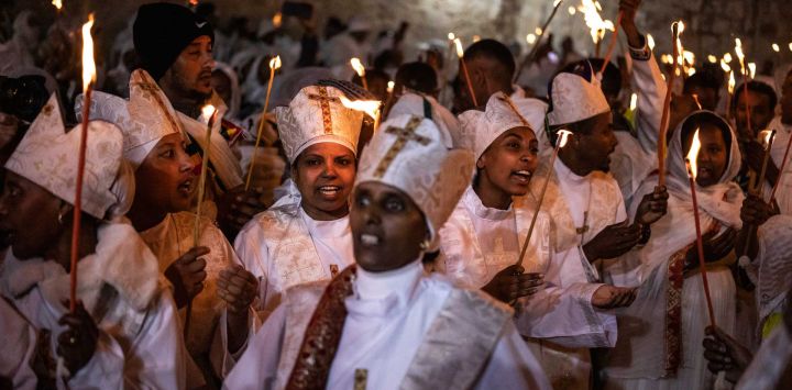 Los fieles cristianos ortodoxos etíopes cantan y bailan mientras sostienen velas durante su ceremonia anual del Fuego Sagrado en la Iglesia del Santo Sepulcro de Jerusalén.