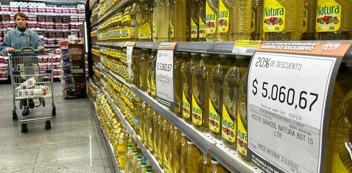 Una mujer empuja un carrito de compras frente a un puesto de aceite de girasol en venta en un supermercado de Buenos Aires.