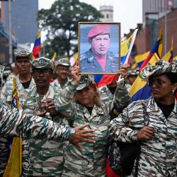 Un miembro de la milicia bolivariana sostiene un retrato del fallecido presidente venezolano Hugo Chávez (1999-2013) durante una marcha que conmemora su regreso al poder tras el fallido golpe de Estado de 2002, en Caracas. | Foto:Federico Parra / AFP
