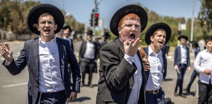 Judíos ultraortodoxos, en su mayoría exentos del servicio militar, protestan contra el reclutamiento obligatorio a la entrada de Tel Hashomer, el centro de reclutamiento del ejército israelí, en Ramat-Gan. El primer ministro de Israel, que depende de sus aliados del partido ultraortodoxo para mantenerse en el poder, ha empleado diversas tácticas para retrasar la aprobación de la legislación que permitiría el alistamiento de los judíos ultraortodoxos, quienes gozan de una amplia exención del servicio militar. Según una normativa establecida en la creación del país en 1948 —cuando la comunidad ultraortodoxa era pequeña—, los hombres que se dedican a tiempo completo al estudio de los textos sagrados judíos reciben una exención de facto.