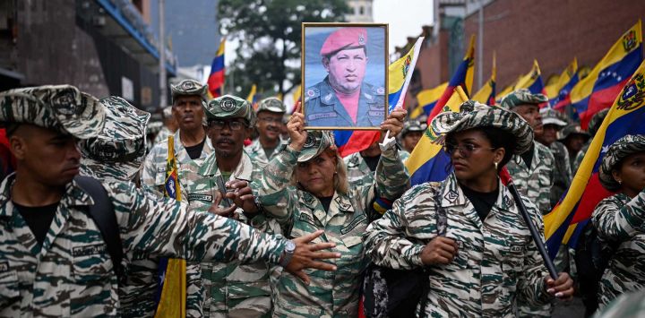 Un miembro de la milicia bolivariana sostiene un retrato del fallecido presidente venezolano Hugo Chávez (1999-2013) durante una marcha que conmemora su regreso al poder tras el fallido golpe de Estado de 2002, en Caracas.