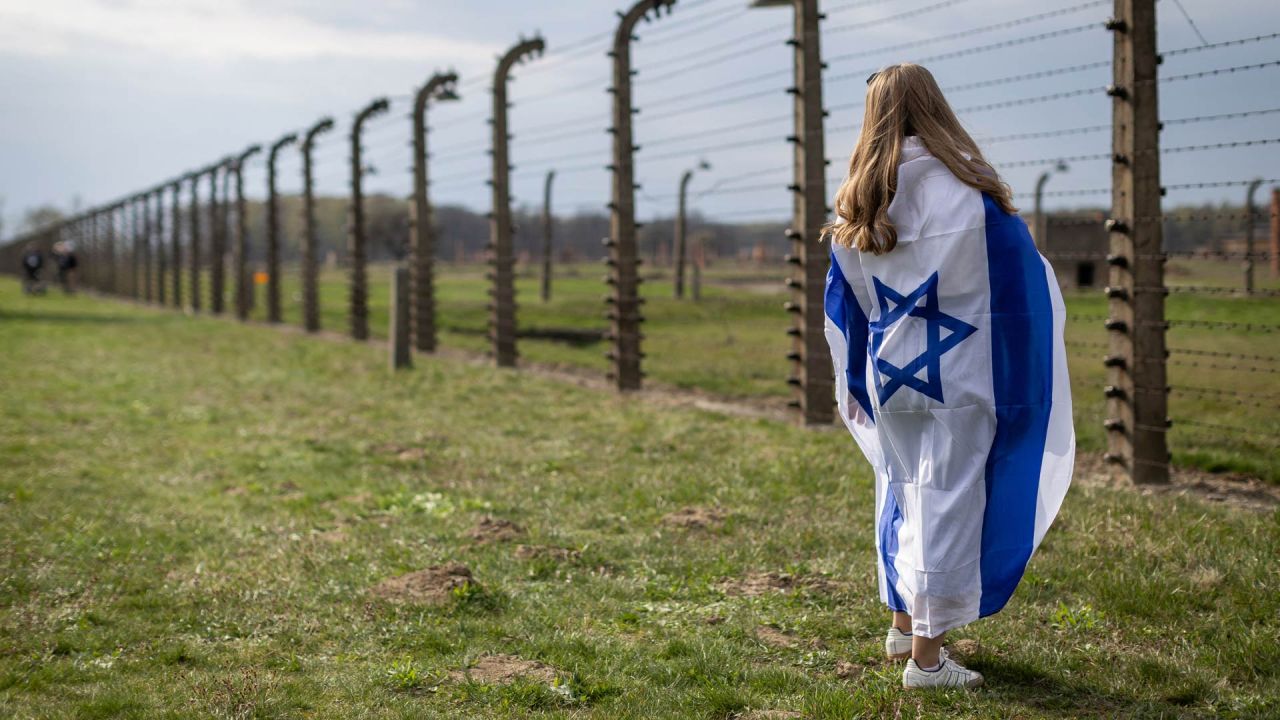 Una mujer envuelta en la bandera de Israel observa la alambrada del antiguo campo de exterminio nazi de Auschwitz-Birkenau en Brzezinka (Birkenau), cerca de Oswiecim, Polonia, durante la Marcha de la Vida anual en honor a las víctimas del Holocausto. | Foto:WOJTEK RADWANSKI / AFP