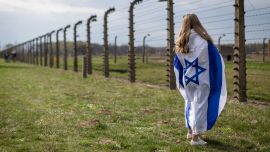 Una mujer envuelta en la bandera de Israel observa la alambrada del antiguo campo de exterminio nazi de Auschwitz-Birkenau en Brzezinka (Birkenau), cerca de Oswiecim, Polonia, durante la Marcha de la Vida anual en honor a las víctimas del Holocausto.