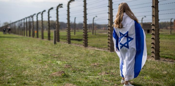 Una mujer envuelta en la bandera de Israel observa la alambrada del antiguo campo de exterminio nazi de Auschwitz-Birkenau en Brzezinka (Birkenau), cerca de Oswiecim, Polonia, durante la Marcha de la Vida anual en honor a las víctimas del Holocausto.