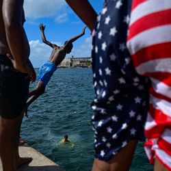 Jóvenes se bañan en el mar frente al Malecón de La Habana, Cuba. | Foto:YAMIL LAGE / AFP