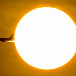 Un avión pasa frente al sol durante el amanecer en Ciudad de Panamá. | Foto:MARTIN BERNETTI / AFP