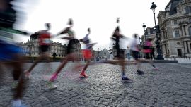 Esta fotografía, tomada con una velocidad de obturación lenta, muestra a los participantes corriendo frente al Museo del Louvre, con la Pirámide del Louvre, diseñada por el arquitecto chino-estadounidense Ieoh Ming Pei, al fondo, durante el Maratón de París.