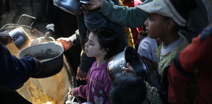Niños palestinos desplazados reciben comida de un comedor social en el campamento de refugiados de Nuseirat, en el centro de la Franja de Gaza. Desde que entraron en vigor los términos del acuerdo de alto el fuego negociado por Estados Unidos el 10 de octubre, Israel mantiene el control de casi la mitad de la Franja de Gaza, incluidas todas sus zonas fronterizas. Cerca de dos millones de personas en Gaza viven en refugios improvisados, y la situación humanitaria sigue siendo crítica, según las agencias de ayuda.