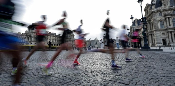 Esta fotografía, tomada con una velocidad de obturación lenta, muestra a los participantes corriendo frente al Museo del Louvre, con la Pirámide del Louvre, diseñada por el arquitecto chino-estadounidense Ieoh Ming Pei, al fondo, durante el Maratón de París.