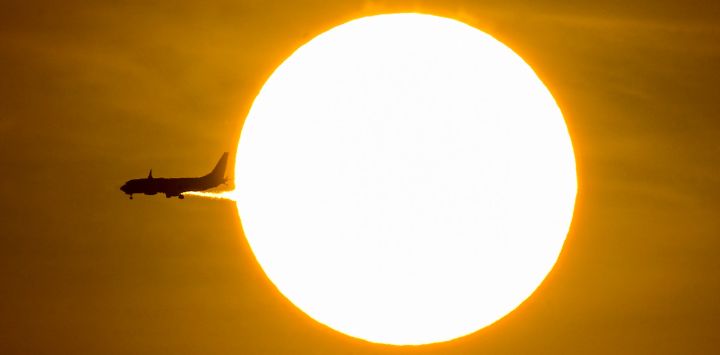 Un avión pasa frente al sol durante el amanecer en Ciudad de Panamá.