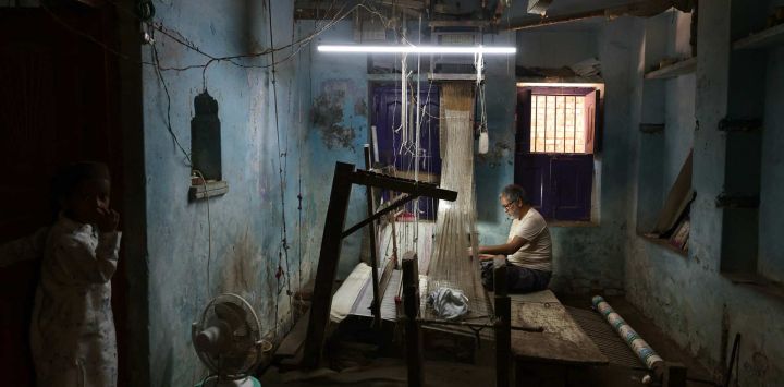 Un niño observa a un artesano mientras teje un sari Banarasi en un telar manual en un taller en Varanasi, India.
