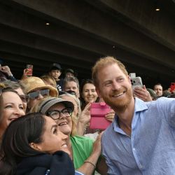 El príncipe Harry de Gran Bretaña, duque de Sussex, y su esposa Meghan, duquesa de Sussex, posan para selfies con miembros del público bajo las escalinatas de la emblemática Ópera de Sídney, Australia. | Foto:Saeed Khan / AFP