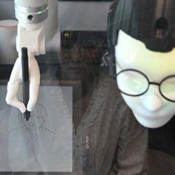 Esta fotografía, muestra a un robot chamán con gafas que ofrece servicios de lectura facial para predecir el futuro mientras dibuja un retrato, en una tienda temática de chamanismo coreano en Seúl. El tintineo de campanillas resuena en un callejón del centro de Seúl, una señal inequívoca de la presencia de un chamán, aunque en este caso el místico es un robot impulsado por inteligencia artificial. | Foto:Jung Yeon-je / AFP