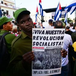 Un miembro del Ministerio del Interior sostiene un cartel con la inscripción "¡Viva nuestra revolución socialista!" durante las celebraciones del 65 aniversario de la invasión de Bahía de Cochinos y la declaración del carácter socialista de la Revolución Cubana en La Habana. Entre el 15 y el 19 de abril de 1961, unos 1400 combatientes anticastristas, entrenados y financiados por la CIA, intentaron desembarcar en Bahía de Cochinos, a unos 250 kilómetros al sur de La Habana, pero fracasaron en su intento de derrocar al régimen comunista de Fidel Castro. | Foto:YAMIL LAGE / AFP