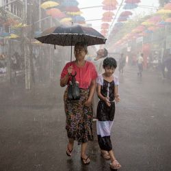 Varias personas caminan bajo aspersores durante las celebraciones del festival del agua del Año Nuevo Budista de Myanmar, también conocido como Thingyan, en Yangon. | Foto:Sai Aung Main / AFP