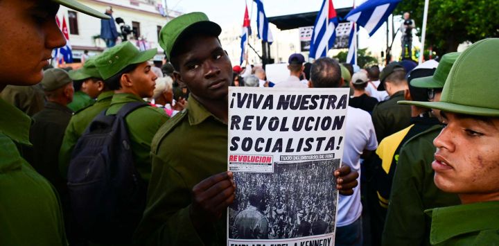 Un miembro del Ministerio del Interior sostiene un cartel con la inscripción "¡Viva nuestra revolución socialista!" durante las celebraciones del 65 aniversario de la invasión de Bahía de Cochinos y la declaración del carácter socialista de la Revolución Cubana en La Habana. Entre el 15 y el 19 de abril de 1961, unos 1400 combatientes anticastristas, entrenados y financiados por la CIA, intentaron desembarcar en Bahía de Cochinos, a unos 250 kilómetros al sur de La Habana, pero fracasaron en su intento de derrocar al régimen comunista de Fidel Castro.
