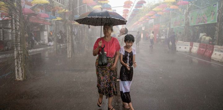 Varias personas caminan bajo aspersores durante las celebraciones del festival del agua del Año Nuevo Budista de Myanmar, también conocido como Thingyan, en Yangon.