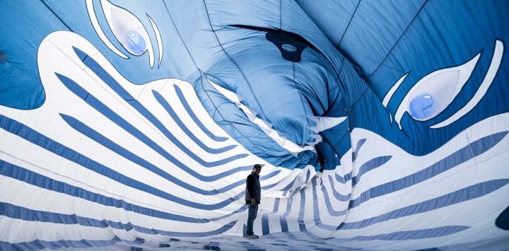 Un participante camina a través de una cometa con forma de ballena durante el 39º Festival Internacional de Cometas (RICV) en la playa de Berck-sur-Mer, al norte de Francia. Unos 450 aficionados a las cometas de 28 países asistieron al 39º Festival Internacional de Cometas de Berck-sur-Mer.