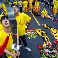 Bailarines de la danza del león observan los petardos mientras se preparan para la peregrinación anual de Dajia Mazu en Taichung, Taiwán. | Foto:cheng-chia huang / AFP