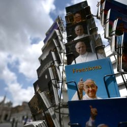Postales con retratos del Papa Francisco y del Papa León XIV se exhiben a la venta en la Via della Conciliazione, con la Basílica de San Pedro al fondo, en Roma. Hoy se celebrará una misa en la Basílica de Santa María la Mayor en Roma para conmemorar el primer aniversario de la muerte del Papa Francisco. | Foto:Filippo Monteforte / AFP