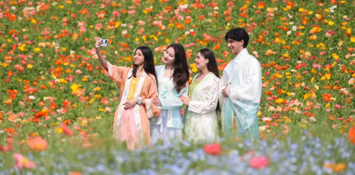 Imagen de estudiantes extranjeros tomándose fotografías con flores, en el poblado de Baitu de Jurong, en la provincia de Jiangsu, en el este de China.
