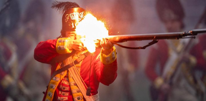 Un recreador histórico vestido como un soldado británico dispara durante una recreación de la Batalla de Lexington y Concord, como parte de las celebraciones del Día del Patriota en Lexington, Massachusetts. Se conmemoró el 250 aniversario de la Batalla de Lexington y Concord, la primera acción militar importante entre el Ejército Británico y las milicias coloniales estadounidenses durante la Guerra de Independencia de Estados Unidos.