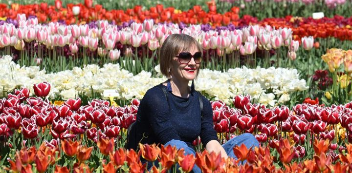 Imagen de una mujer posando para fotografías entre flores en plena floración en un parque, en Valeggio sul Mincio, en Verona, Italia.
