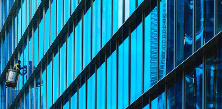 Trabajadores suspendidos en una estructura metálica limpian las ventanas de un edificio de oficinas en Paddington Central, Londres, Inglaterra.