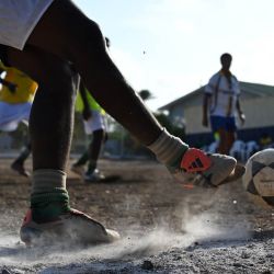 Jugadores de fútbol participan en una sesión de entrenamiento de la escuela de fútbol de la Fundación Bicentini en el barrio de Fuik, al este de Willemstad, en el Caribe neerlandés. Isla pequeña, grandes sueños. El cartel de la selección nacional de fútbol de Curazao cuelga a la entrada de Marchena, un barrio obrero de Willemstad, la capital del territorio más pequeño que jamás se haya clasificado para un Mundial. | Foto:RAUL ARBOLEDA / AFP